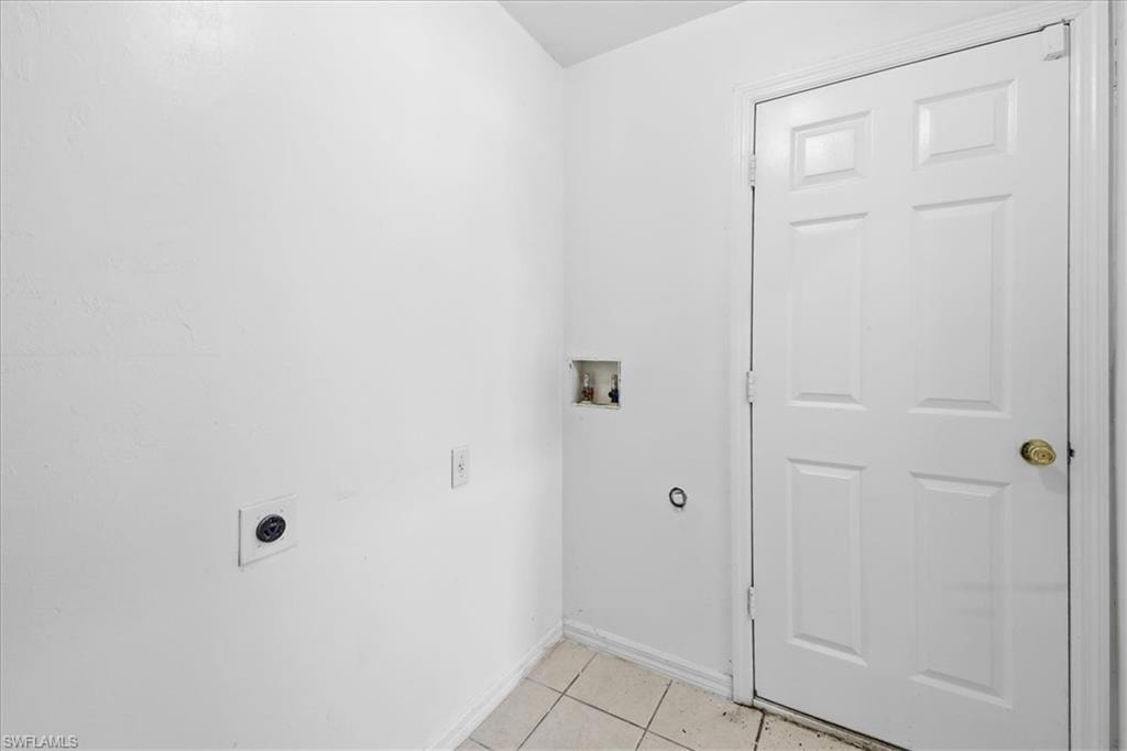 Utility area featuring white paneled door, ceramic tile flooring, and dedicated laundry hookups