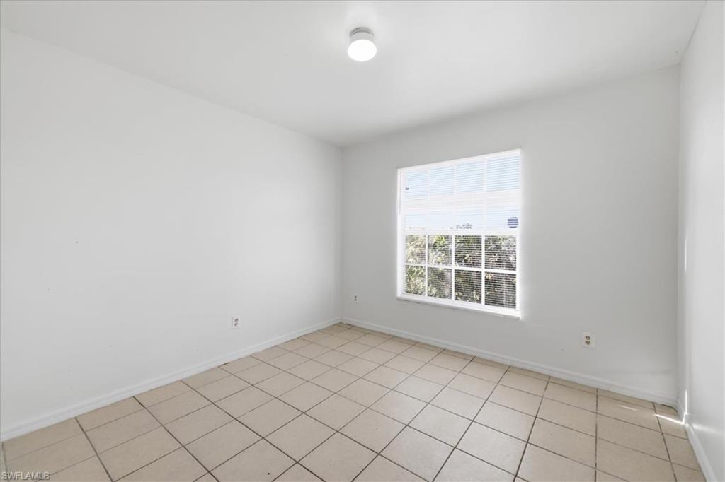 Room featuring a single paned window with grid, white walls, and light-colored tile flooring