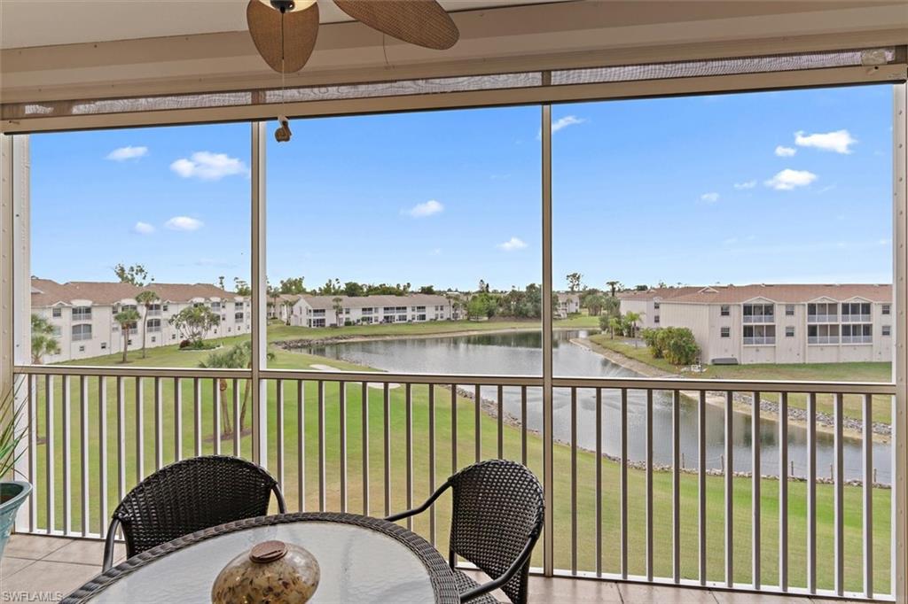 Screened balcony featuring a ceiling fan, offering broad water and green space vistas, complemented by distant architecture