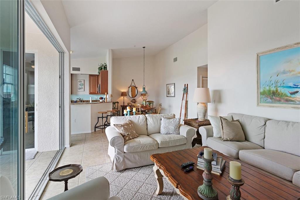 Spacious living area featuring high ceilings, tile flooring, and sliding glass doors opening to the exterior