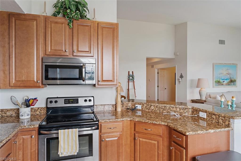 Kitchen featuring wood-finish cabinetry, stainless steel microwave, and electric range