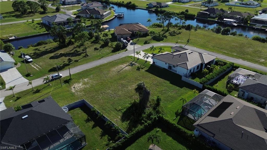 Expansive undeveloped lot featuring a grass expanse and mature palm trees, with paved road frontage and surrounded by residential properties