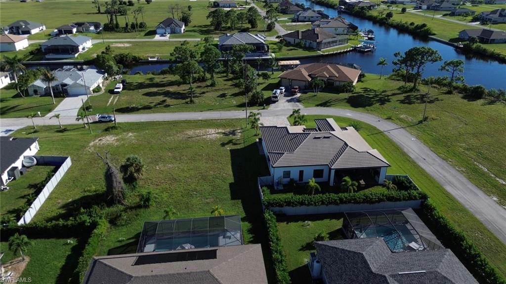 Expansive undeveloped lot with surrounding residential properties, featuring a paved road and mature greenery