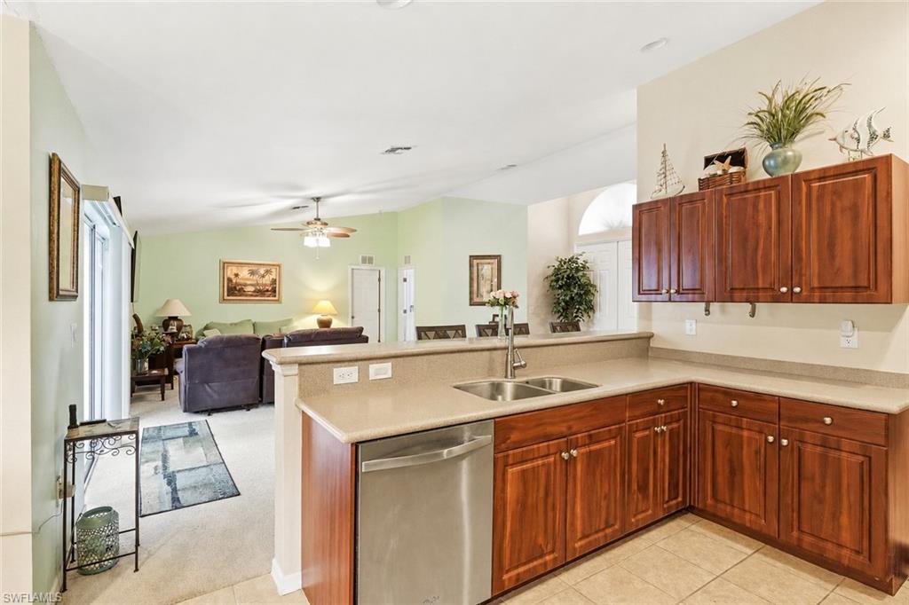 Virtually Staged Kitchen featuring wood-finish cabinetry, stainless steel dishwasher, and a double basin sink with a chrome faucet