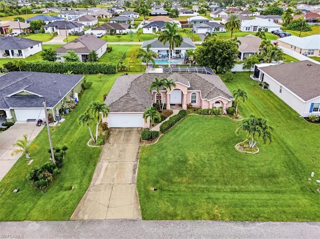 Expansive property featuring a screened-in swimming pool, shingle roof, mature landscaping, and a concrete driveway