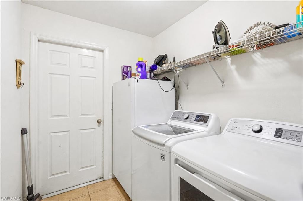 Virtually Staged Dedicated laundry area featuring tile flooring, a paneled door, and a wall-mounted wire shelving system