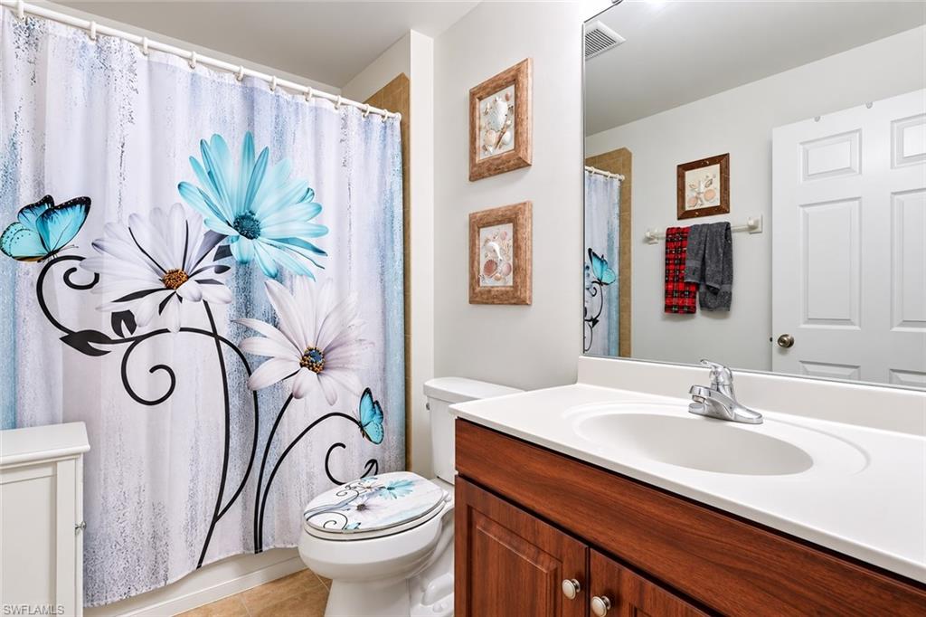 Full bathroom featuring a wood-finish vanity with a white countertop and integrated sink, a large wall-mounted mirror, and a white two-panel door