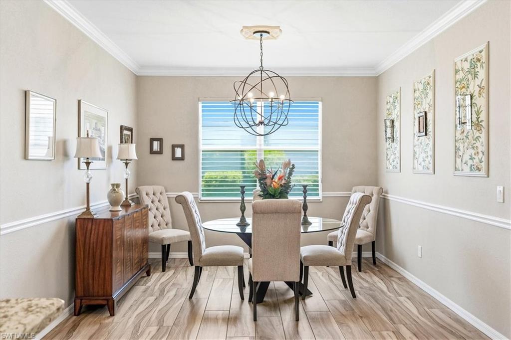 Dining area featuring wood-finish flooring, a contemporary chandelier, crown molding, and wainscoting details