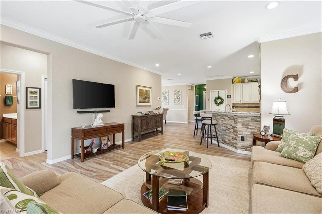 Open concept living area featuring wood-finish flooring, crown molding, and recessed lighting