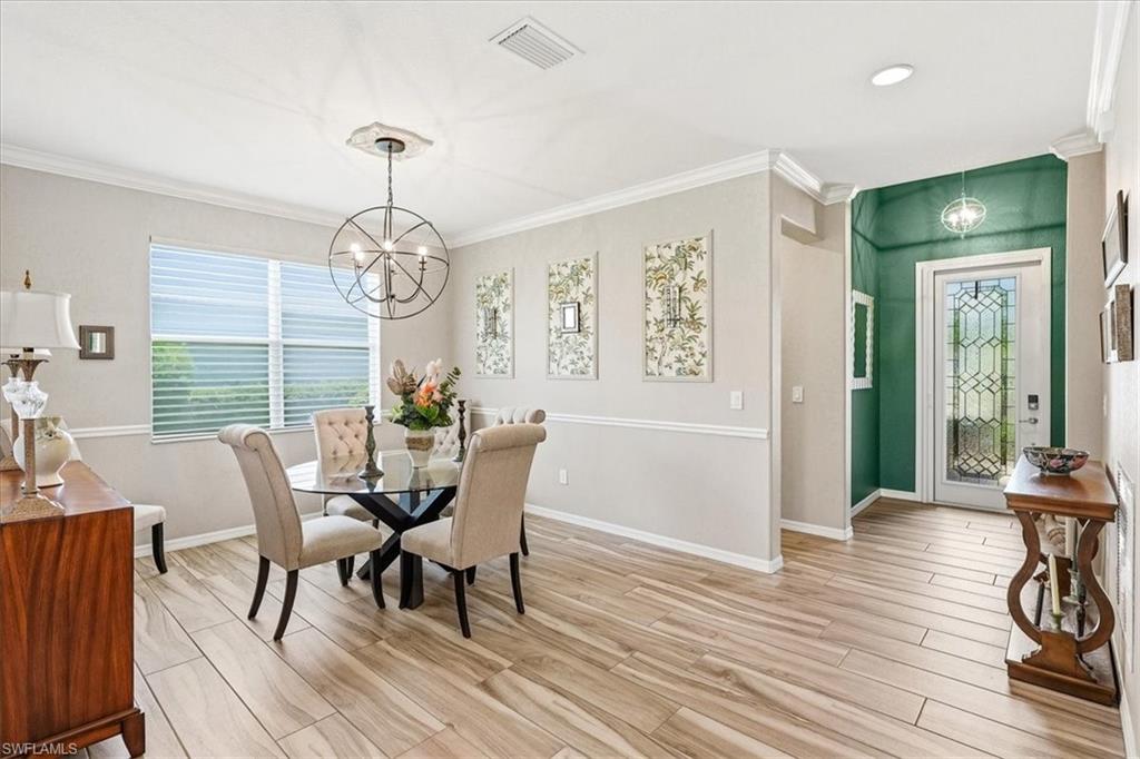 Open concept interior featuring wood-finish flooring, a decorative entryway with a paneled glass door, and a dining area with a contemporary chandelier