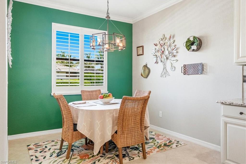 Dining area featuring a prominent window with white plantation shutters, a modern chandelier, and a decorative accent wall