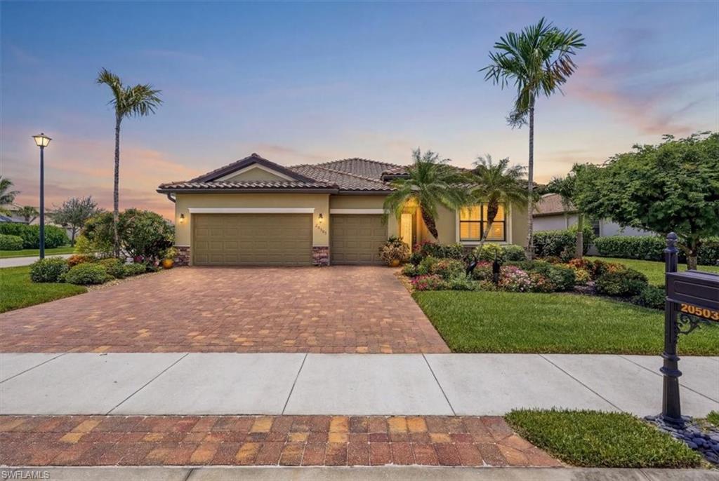 Mediterranean-style residence featuring a tile roof, an expansive paver driveway, and an attached two-car garage