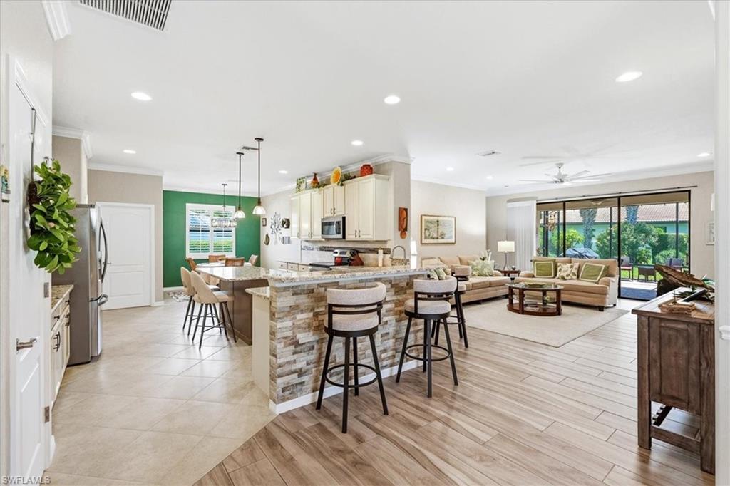 Open concept living area featuring a kitchen island with stone veneer detailing and pendant lighting, wood-finish flooring, recessed lighting, and sliding glass doors