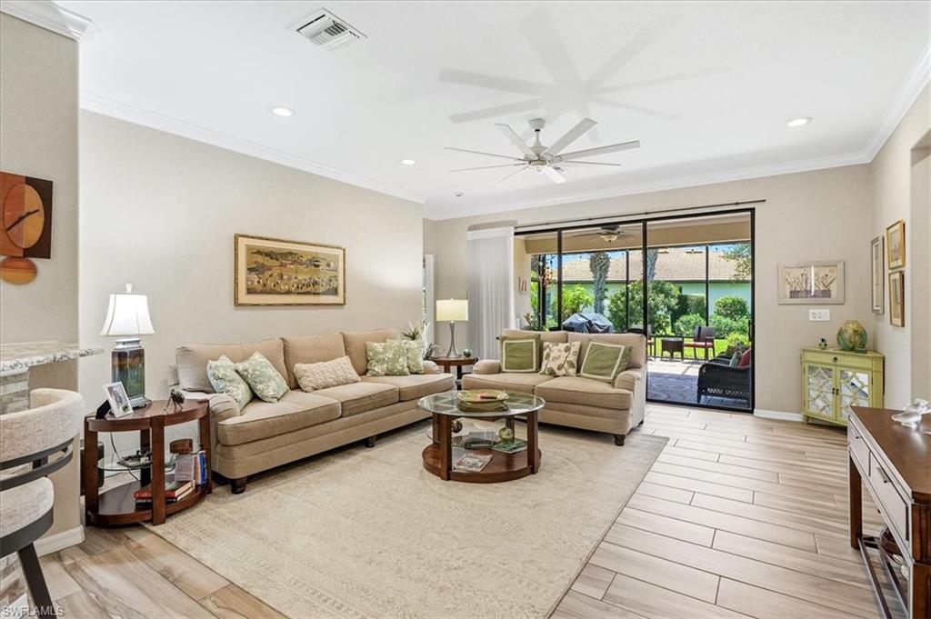 Spacious living area featuring wood-finish flooring, crown molding, and a large ceiling fan