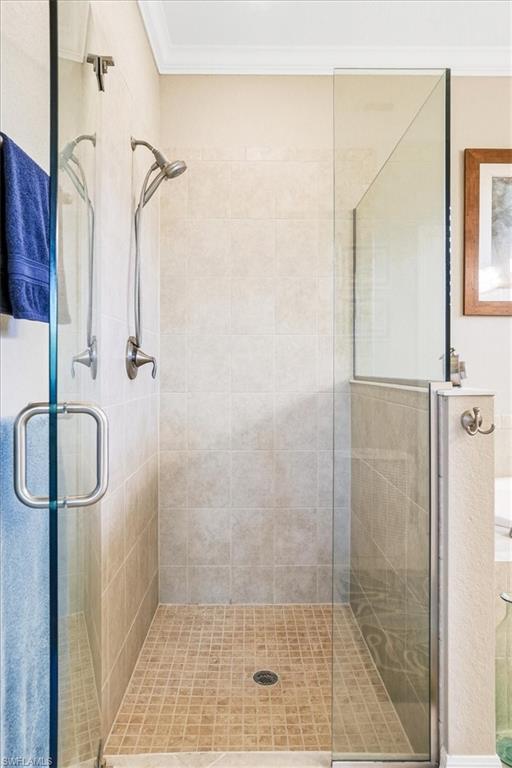 Glass-enclosed shower featuring large format wall tiles and small format floor tiles