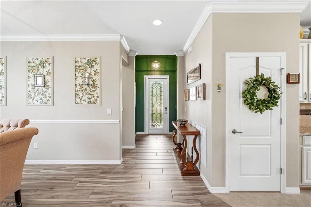 Entryway featuring wood-finish tile flooring, crown molding, and wainscoting