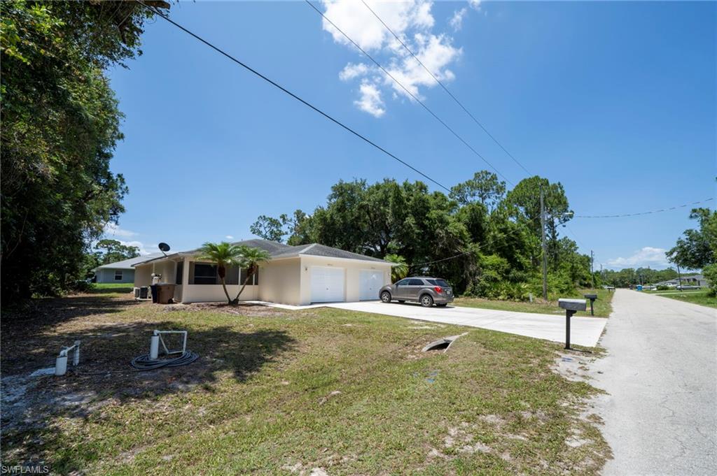 View of property exterior with concrete driveway, a garage, and a lawn