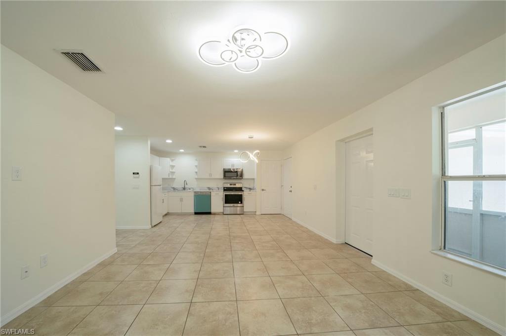 Unfurnished living room featuring light tile patterned floors and a chandelier