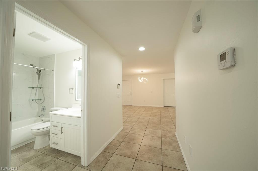 Corridor with light tile patterned floors and recessed lighting