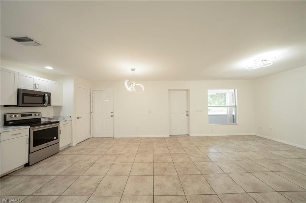 Kitchen with appliances with stainless steel finishes, light countertops, white cabinets, decorative light fixtures, and recessed lighting
