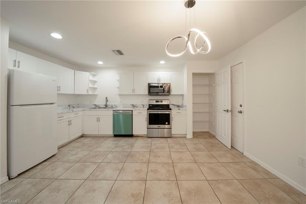 Kitchen with stainless steel appliances, open shelves, recessed lighting, white cabinetry, and a chandelier