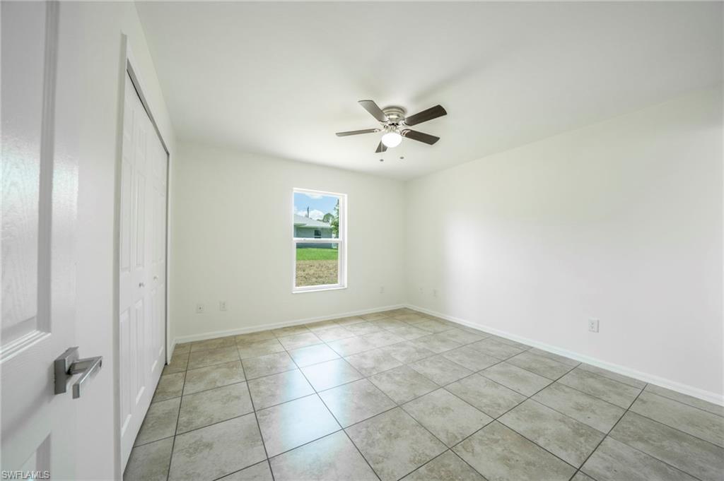 Unfurnished bedroom featuring a closet, light tile patterned floors, and ceiling fan