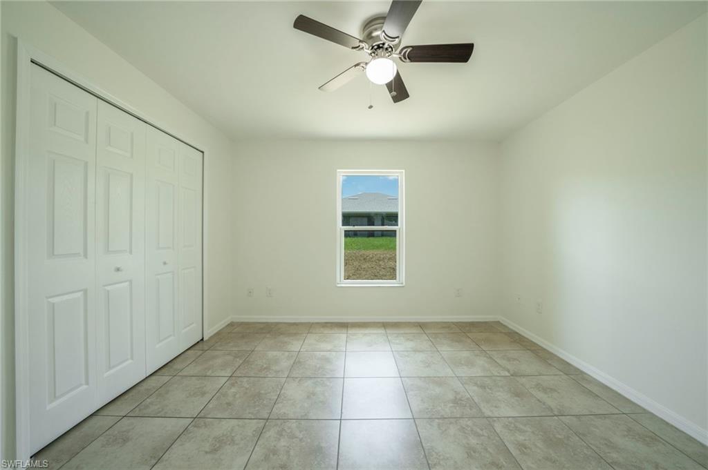 Unfurnished bedroom with a closet, light tile patterned floors, and a ceiling fan