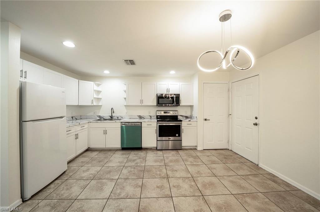 Kitchen featuring open shelves, appliances with stainless steel finishes, light countertops, white cabinets, and light tile patterned floors