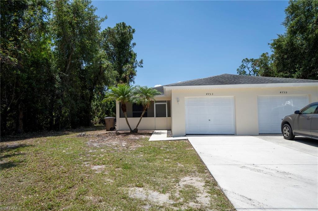 Ranch-style house with stucco siding, driveway, a front lawn, and a garage