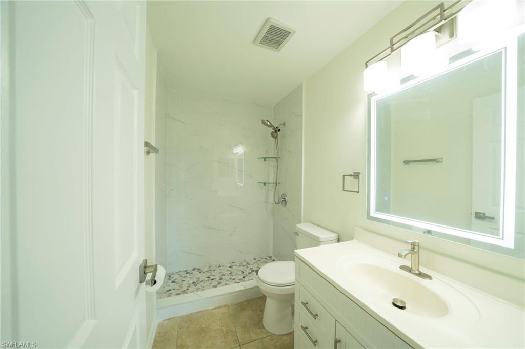 Full bathroom featuring vanity, a marble finish shower, and tile patterned floors