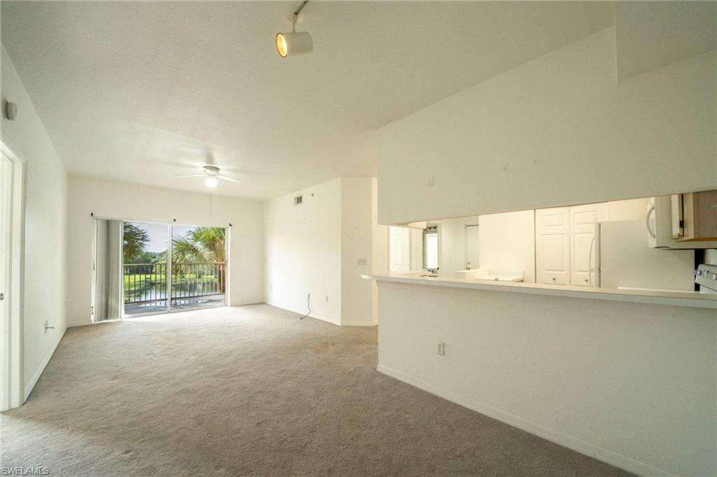 Unfurnished living room featuring a high ceiling, ceiling fan, and light colored carpet