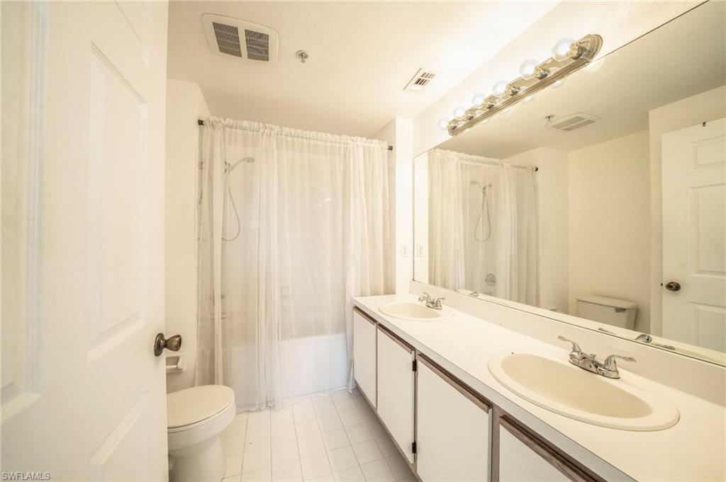 Full bathroom featuring vanity, toilet, tile patterned flooring, and shower / bathtub combination with curtain