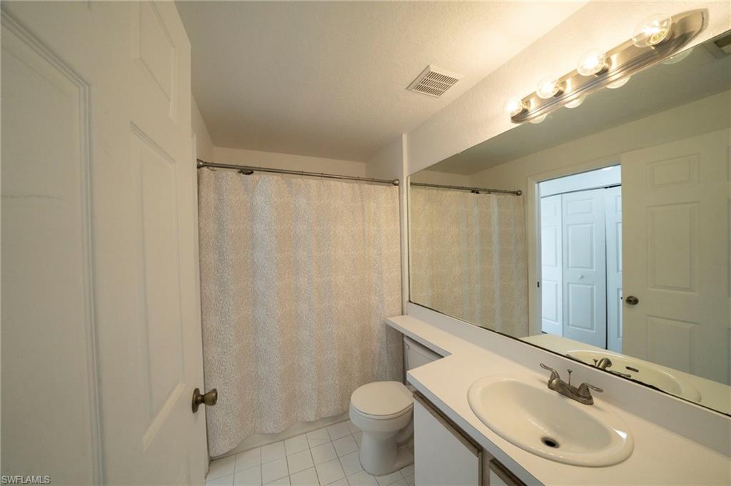 Bathroom with a shower with shower curtain, tile patterned flooring, toilet, and vanity