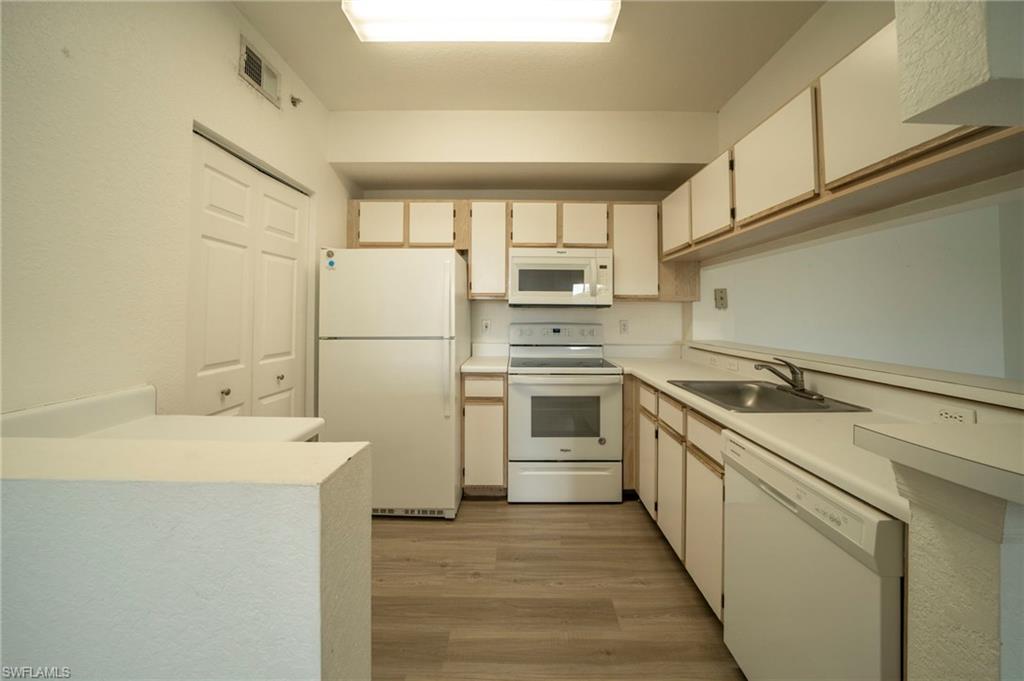 Kitchen with light hardwood / wood-style flooring, sink, and white appliances
