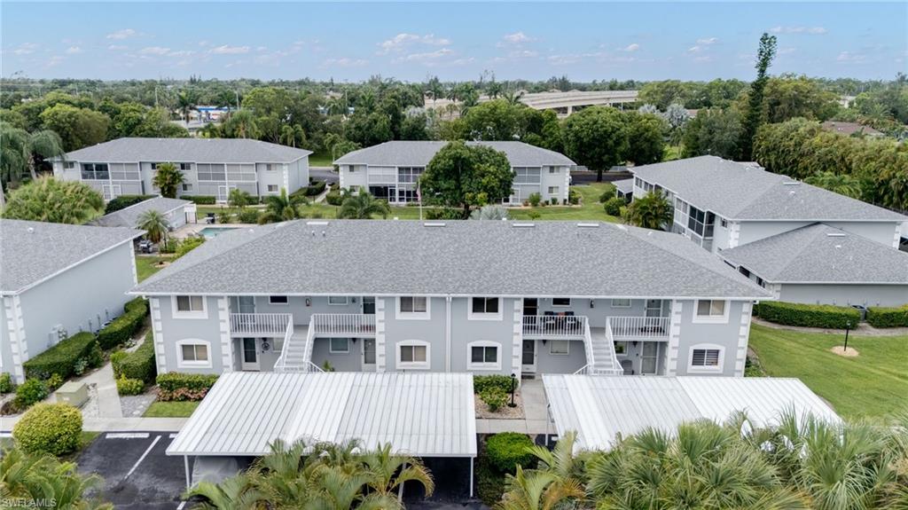 Multi-story residential buildings featuring covered parking, private balconies, and surrounding green spaces with mature trees