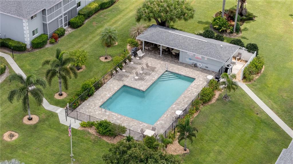 Community swimming pool with surrounding paver deck, perimeter fencing, and an adjacent covered cabana structure