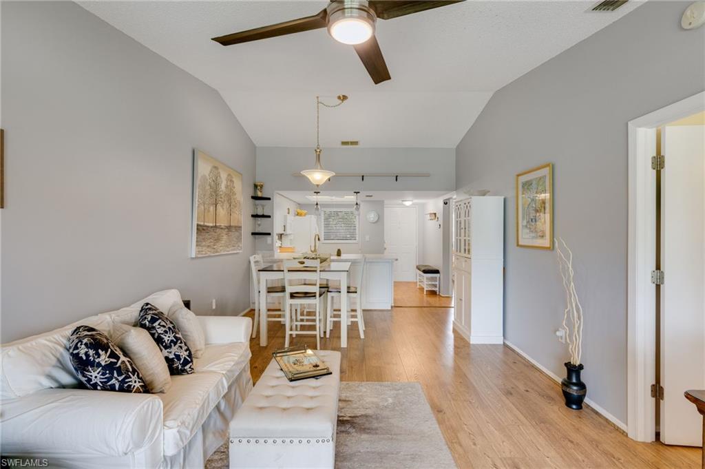 Spacious living area featuring vaulted ceilings, wood-finish flooring, and a ceiling fan with integrated lighting
