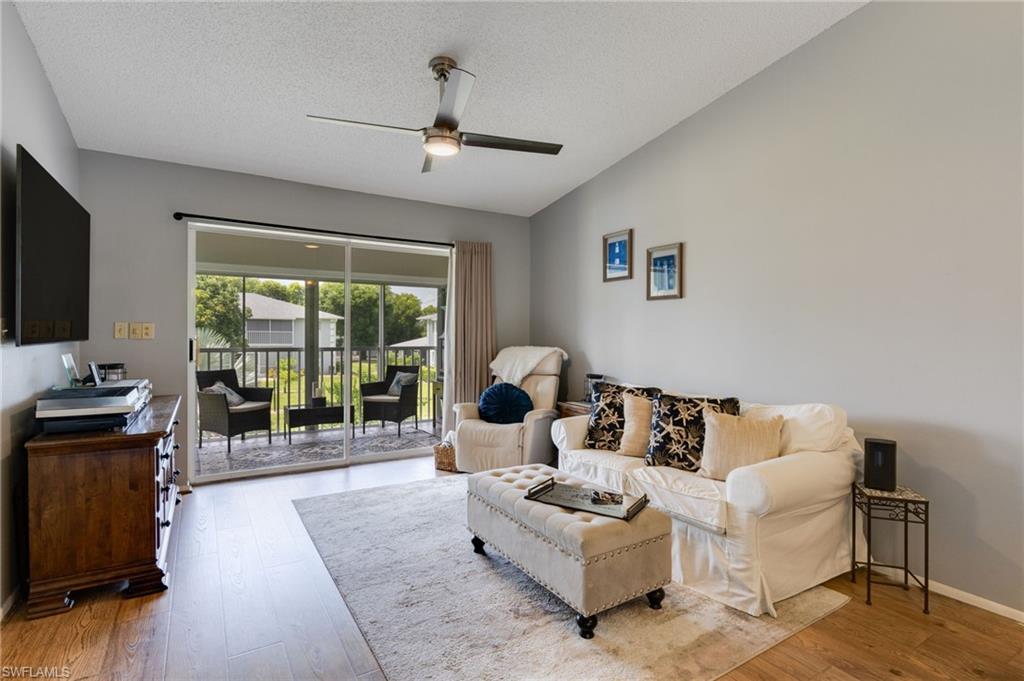 Living space with wood-finish flooring, light gray wall paint, and a ceiling fan with integrated lighting