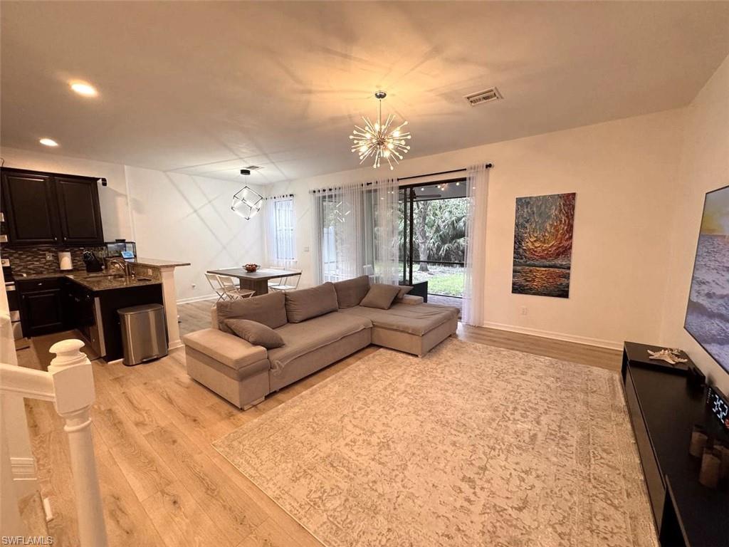 Living room featuring light wood-style floors, a chandelier, and recessed lighting