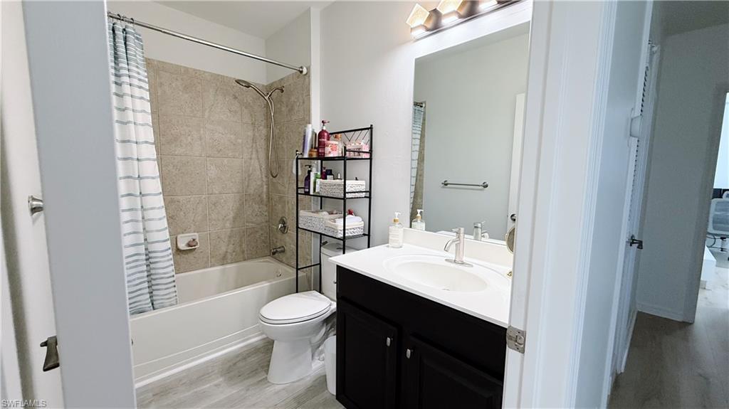 Bathroom featuring shower / bath combo with shower curtain, vanity, and light wood finished floors