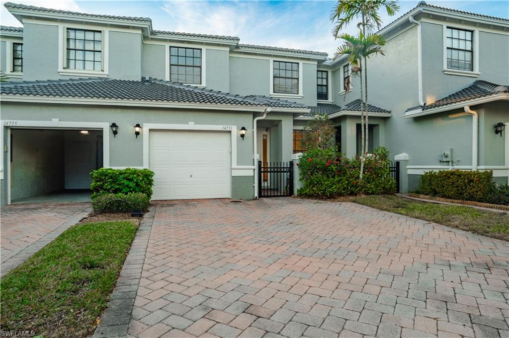 Mediterranean / spanish home with decorative driveway, stucco siding, a gate, and a tiled roof