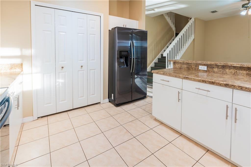 Kitchen featuring stainless steel appliances, white cabinets, light tile patterned flooring, and light stone counters