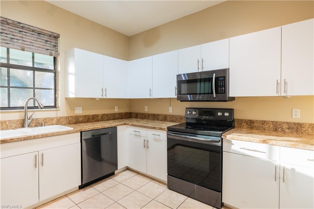 Kitchen featuring black appliances, white cabinets, and light tile patterned floors