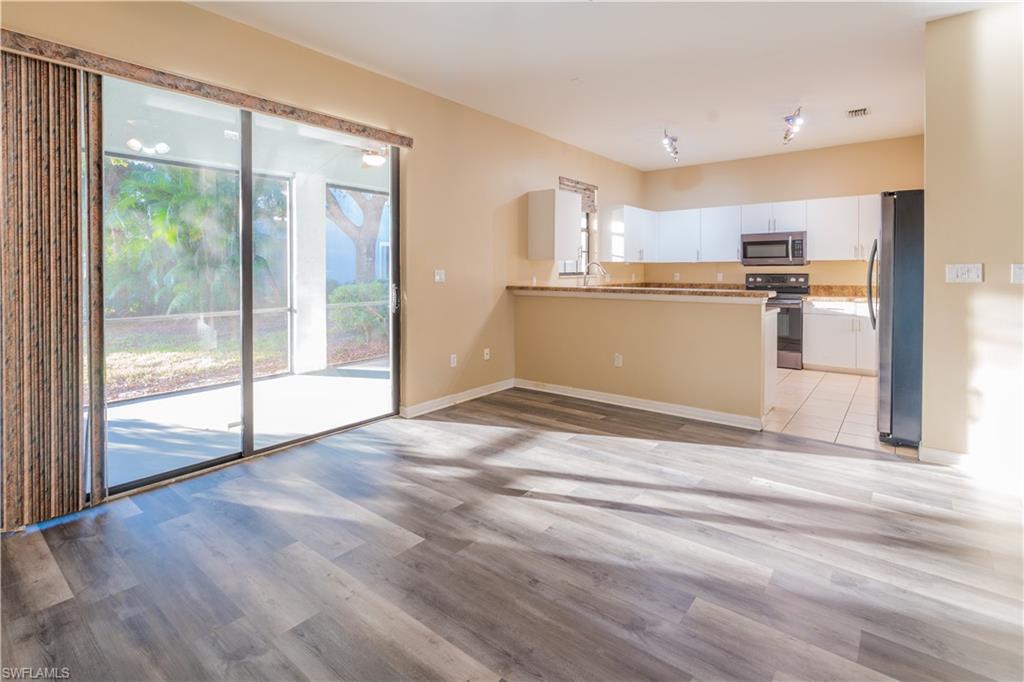 Kitchen with stainless steel appliances, white cabinets, light wood finished floors, and a peninsula