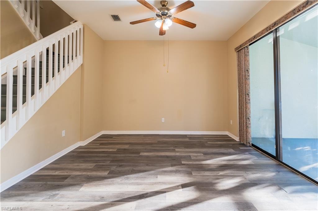 Empty room with a ceiling fan and dark wood-type flooring