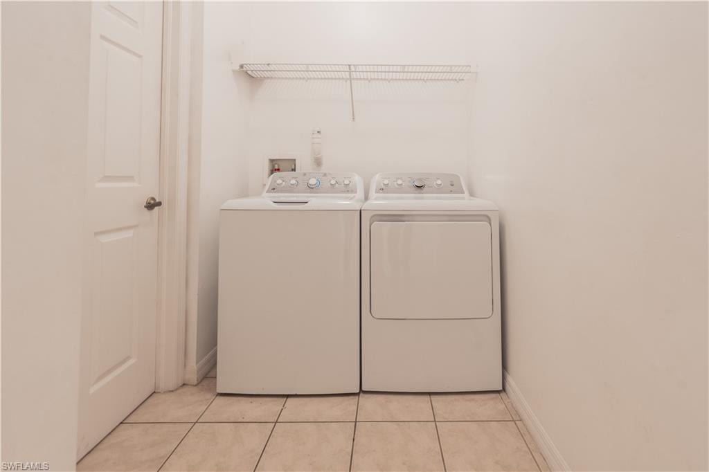 Laundry area featuring light tile patterned flooring and independent washer and dryer