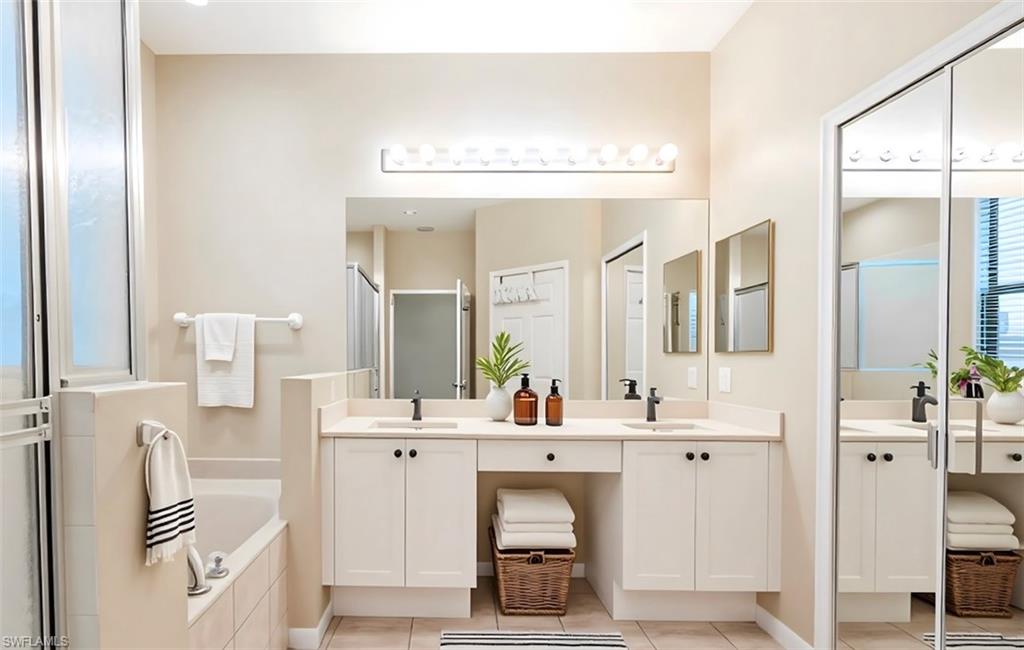 Bathroom with double vanity, a garden tub, a stall shower, and light tile patterned floors