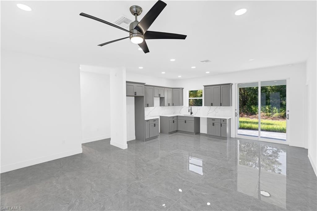 Spacious open-concept living area featuring large format tile flooring, a modern ceiling fan, and recessed lighting