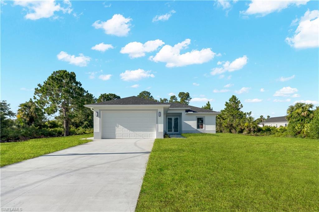 Contemporary single-story residence featuring a two-car garage, concrete driveway, and expansive green lawn