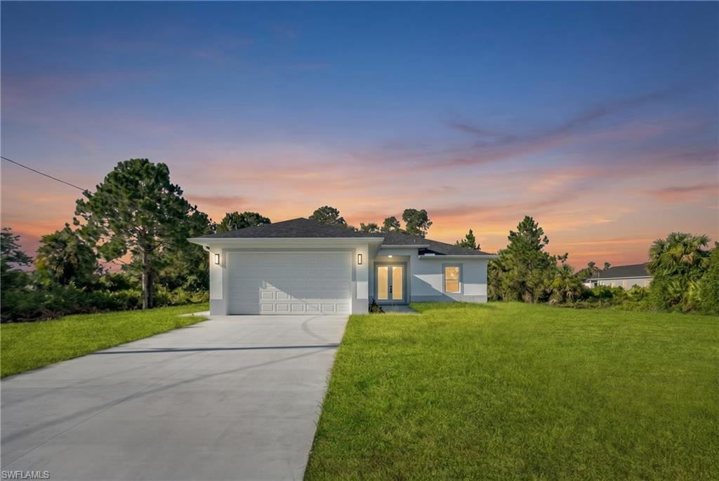 Contemporary single-story residence featuring a two-car garage, concrete driveway, and a manicured lawn